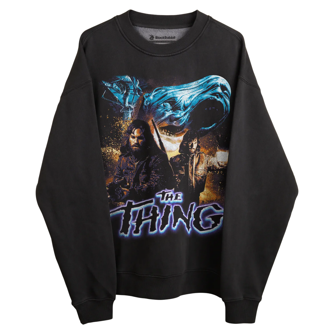 Black long-sleeved sweatshirt with ’the thing’ graphic design featuring two characters and a blue wave-like element.