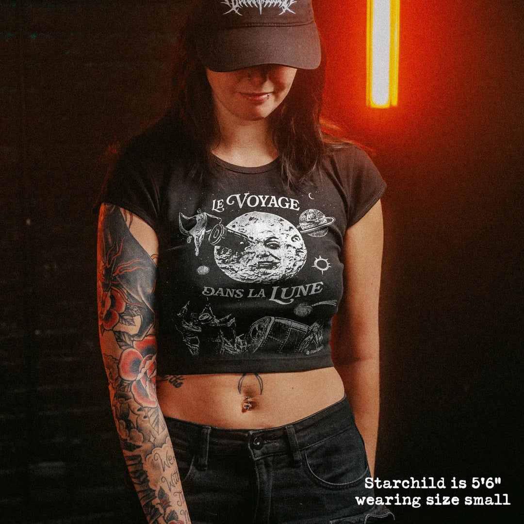 Female model wearing cropped baby tee with a trip to the moon graphic
