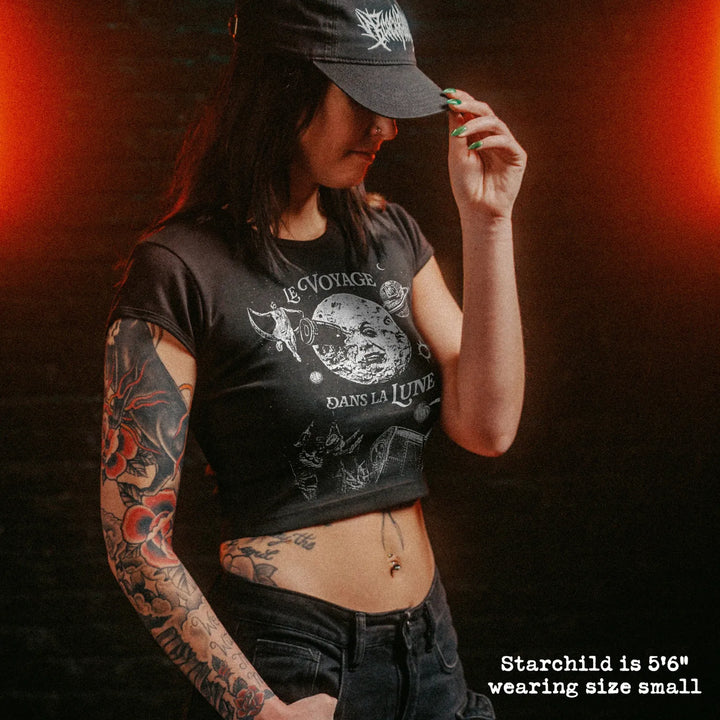 Female model wearing cropped baby tee with a trip to the moon graphic
