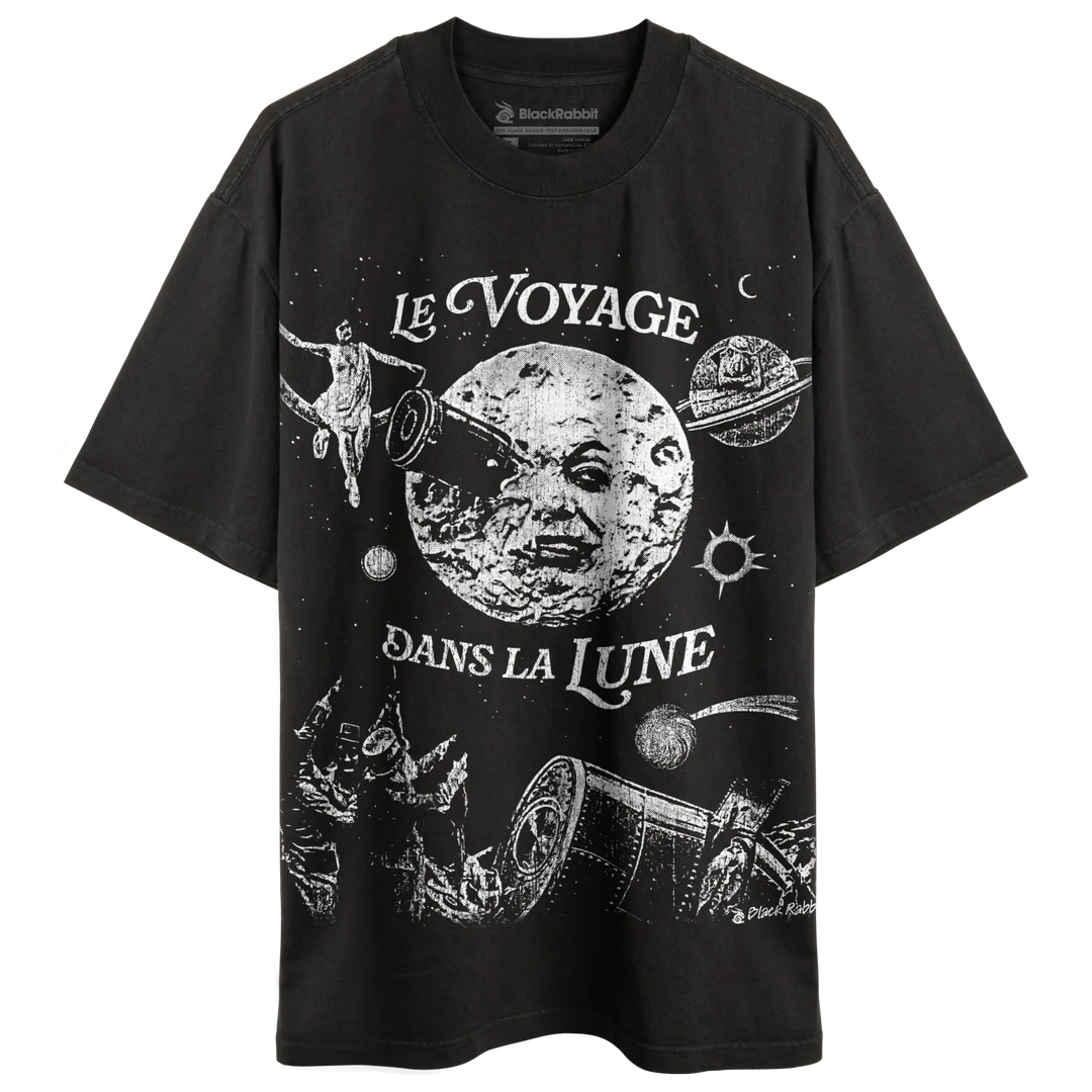 A black short-sleeved t-shirt with a white graphic print depicting a celestial scene inspired by ’Le Voyage dans la Lune.’