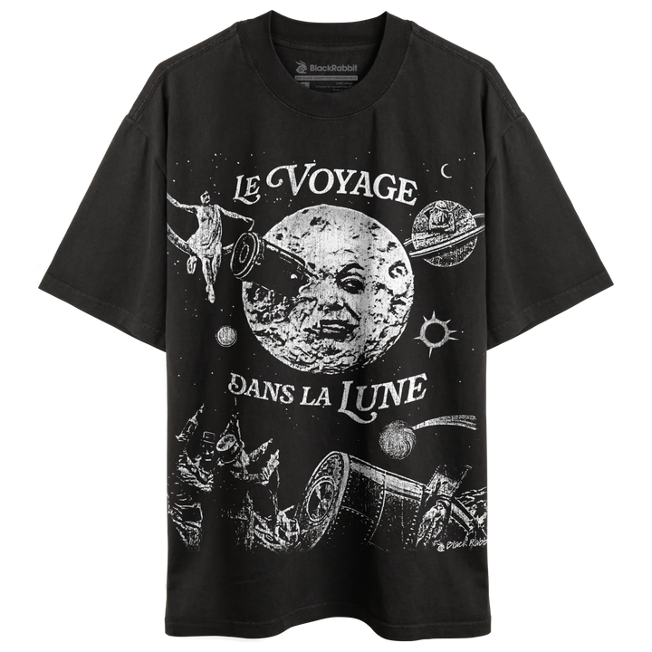 A black short-sleeved t-shirt with a white graphic print depicting a celestial scene inspired by ’Le Voyage dans la Lune.’