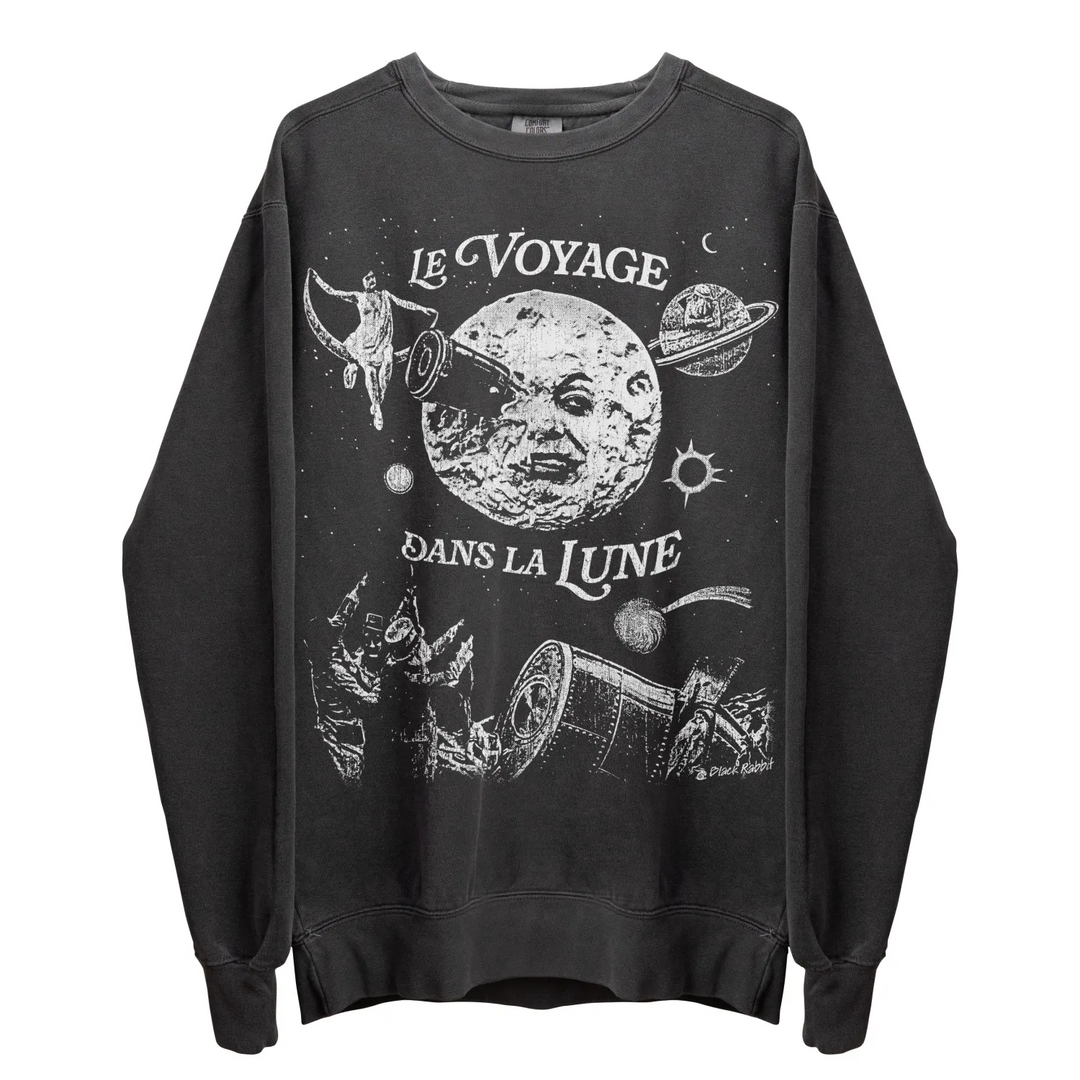 A long-sleeved dark grey sweatshirt with a white graphic print depicting a moon with a face, a rocket, and ’LE VOYAGE DANS LA LUNE’ text.