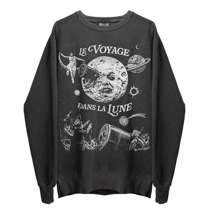 A long-sleeved dark grey sweatshirt with a white graphic print depicting a moon with a face, a rocket, and ’LE VOYAGE DANS LA LUNE’ text.
