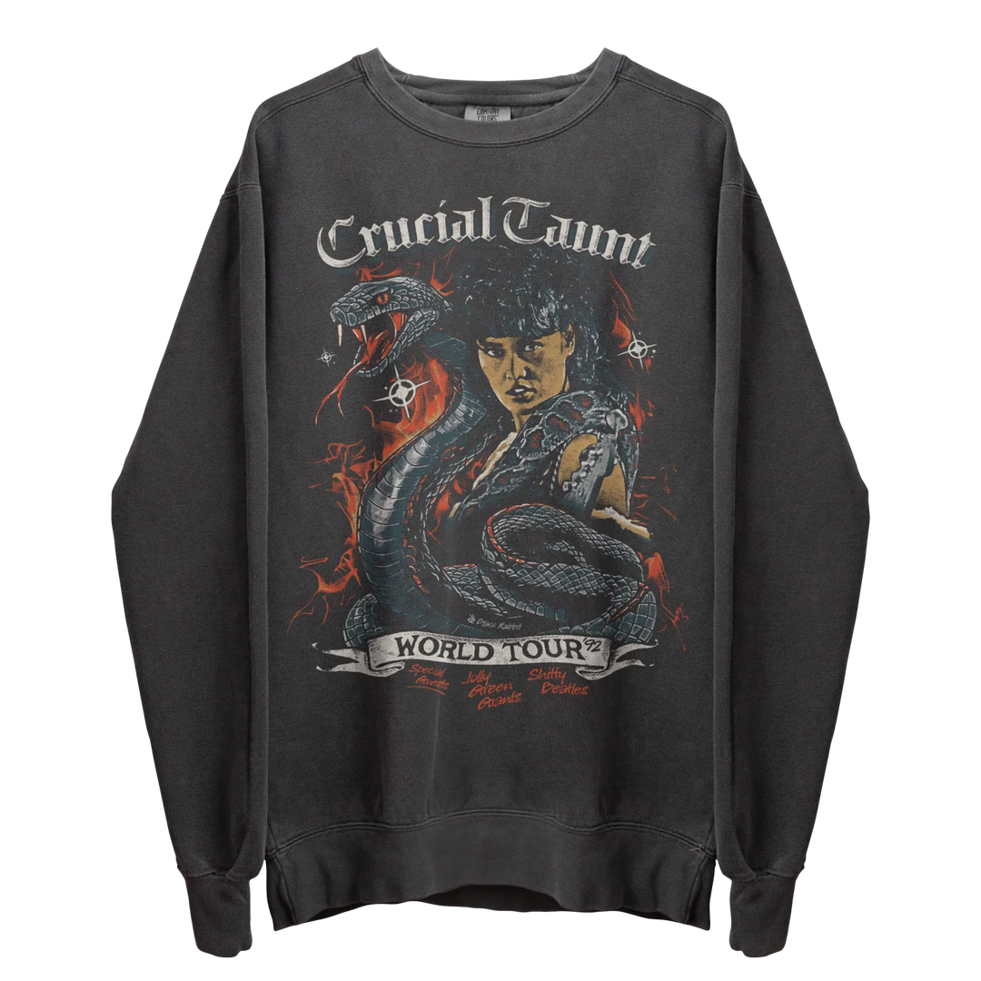 Dark gray crewneck sweatshirt with a graphic print featuring a woman, a snake, and ’CRUCIAL TAUNT WORLD TOUR’ text.
